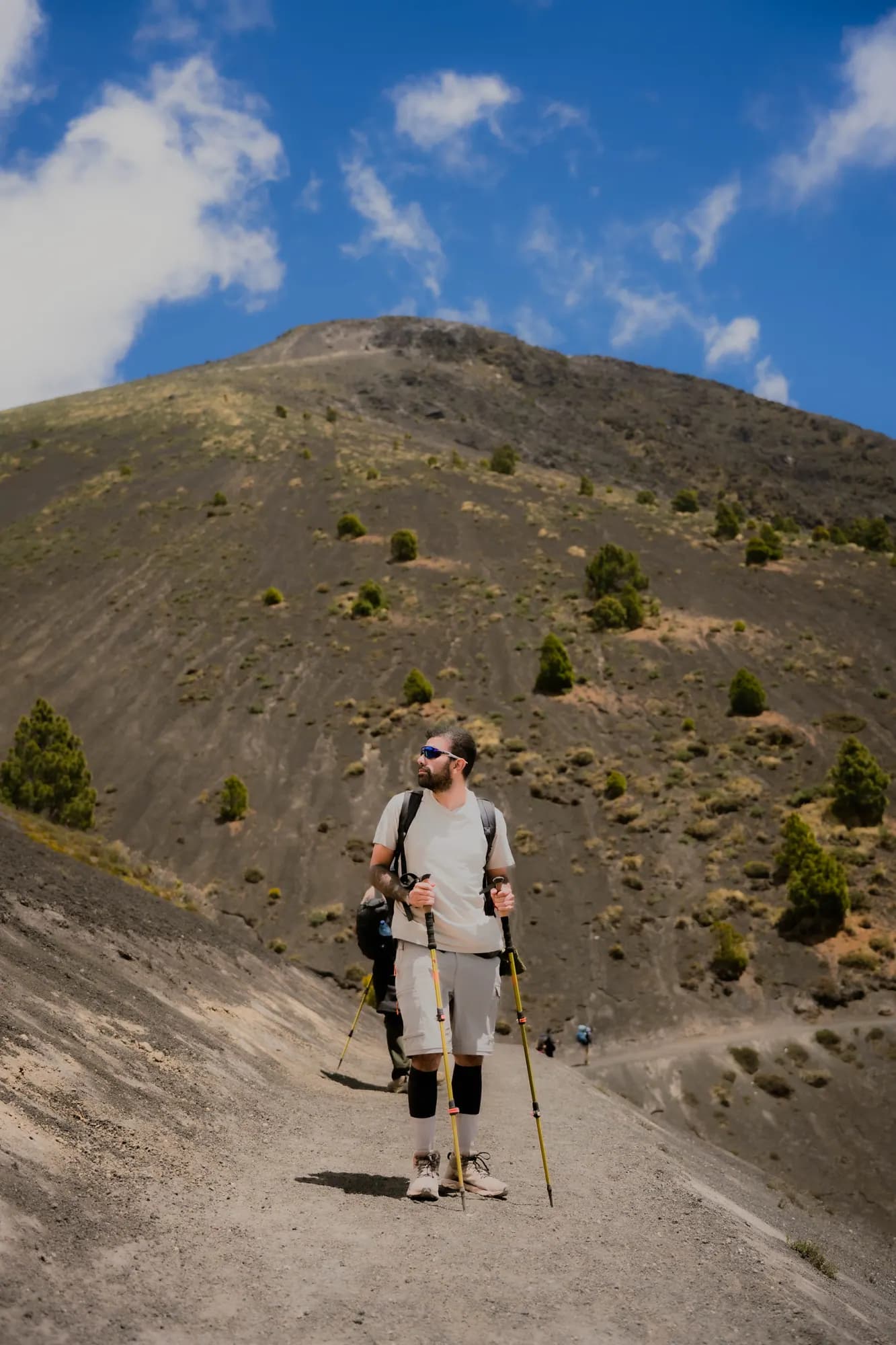 A hiker walking down the volcanic sand trail