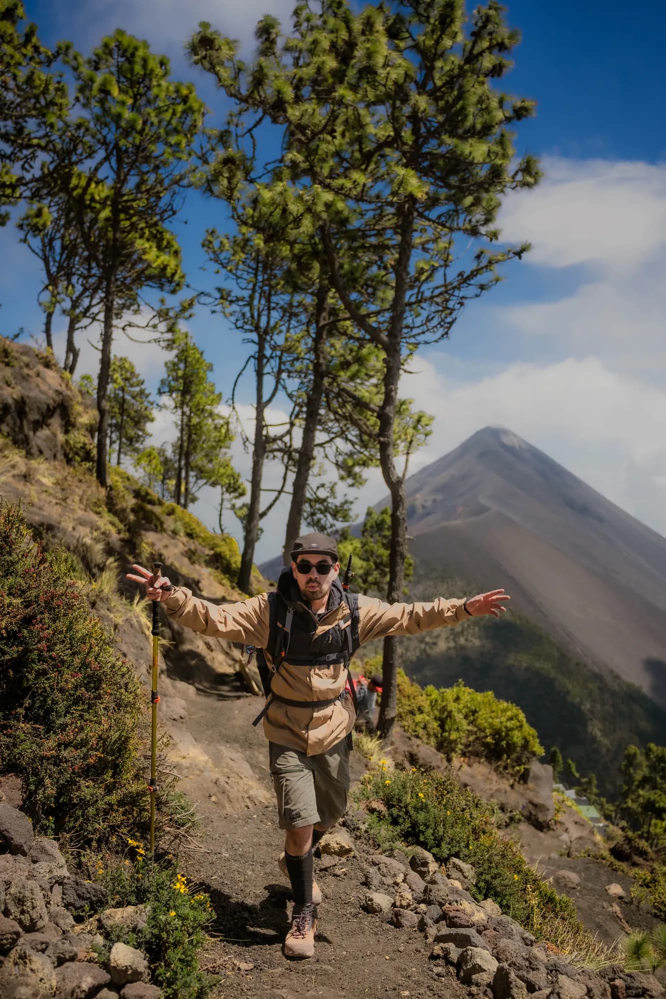 A hiker with open arms among the pines, Fuego behind