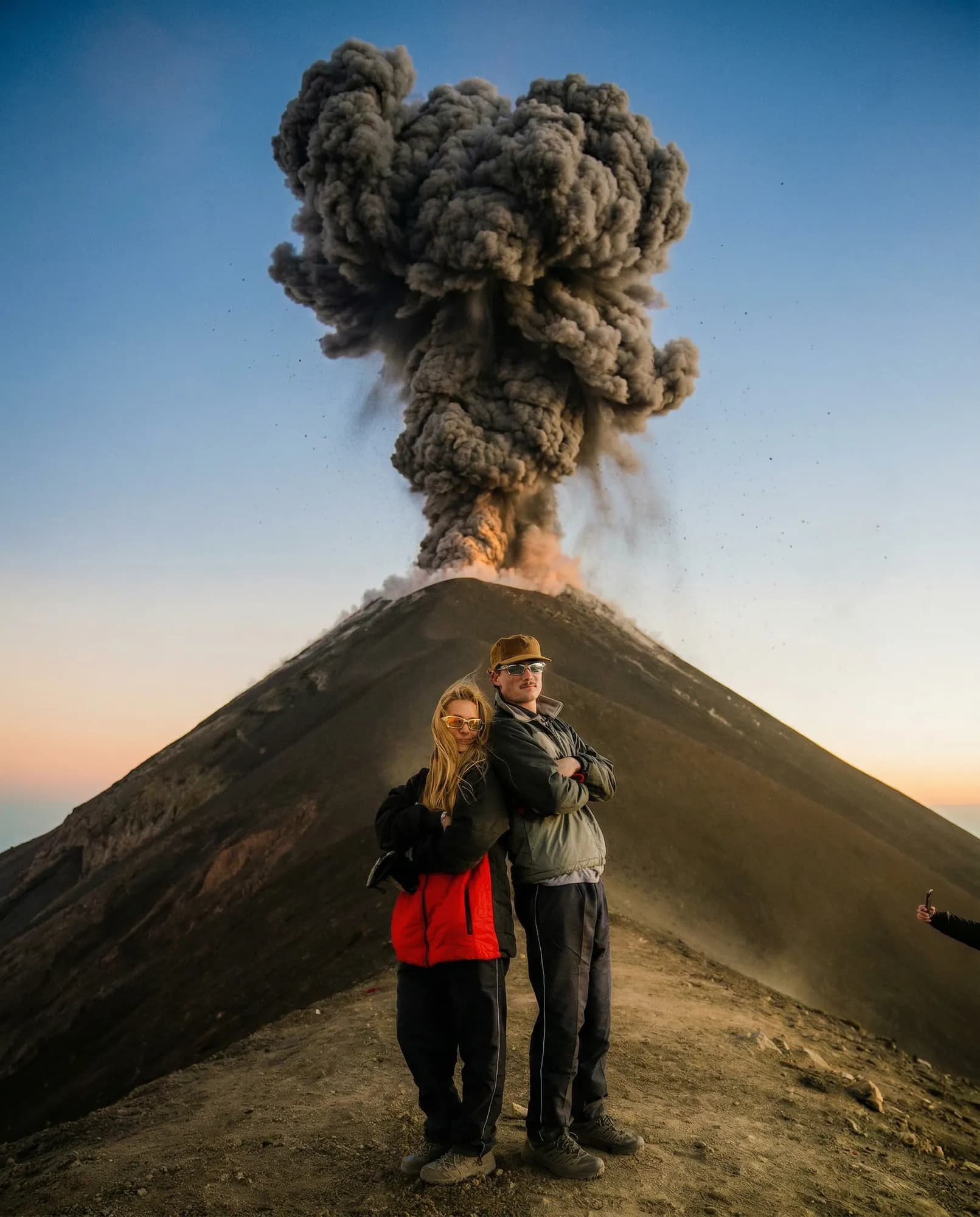 A couple in front of an eruption of Volcán de Fuego