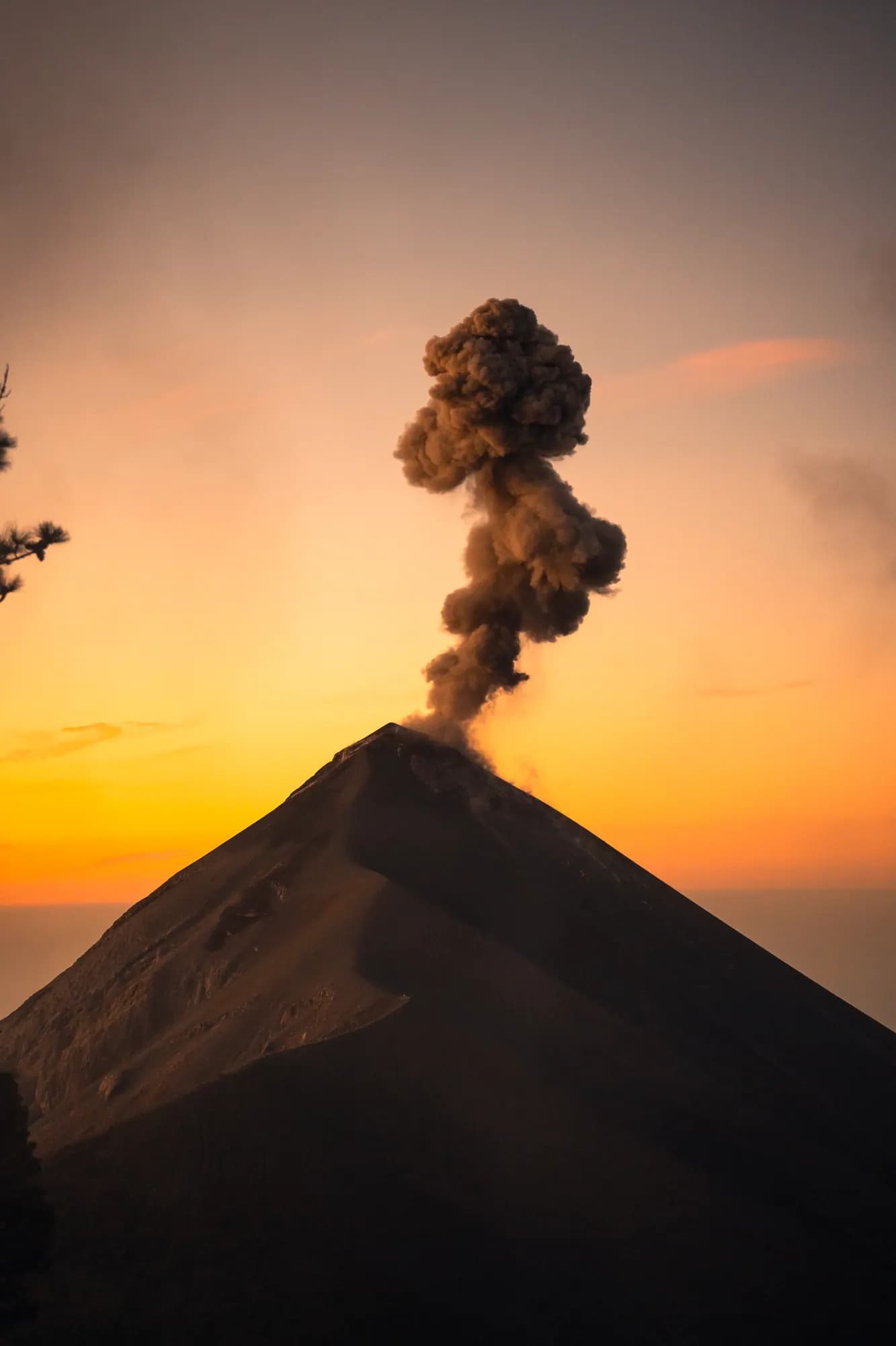 Volcán de Fuego erupting against an orange sunset